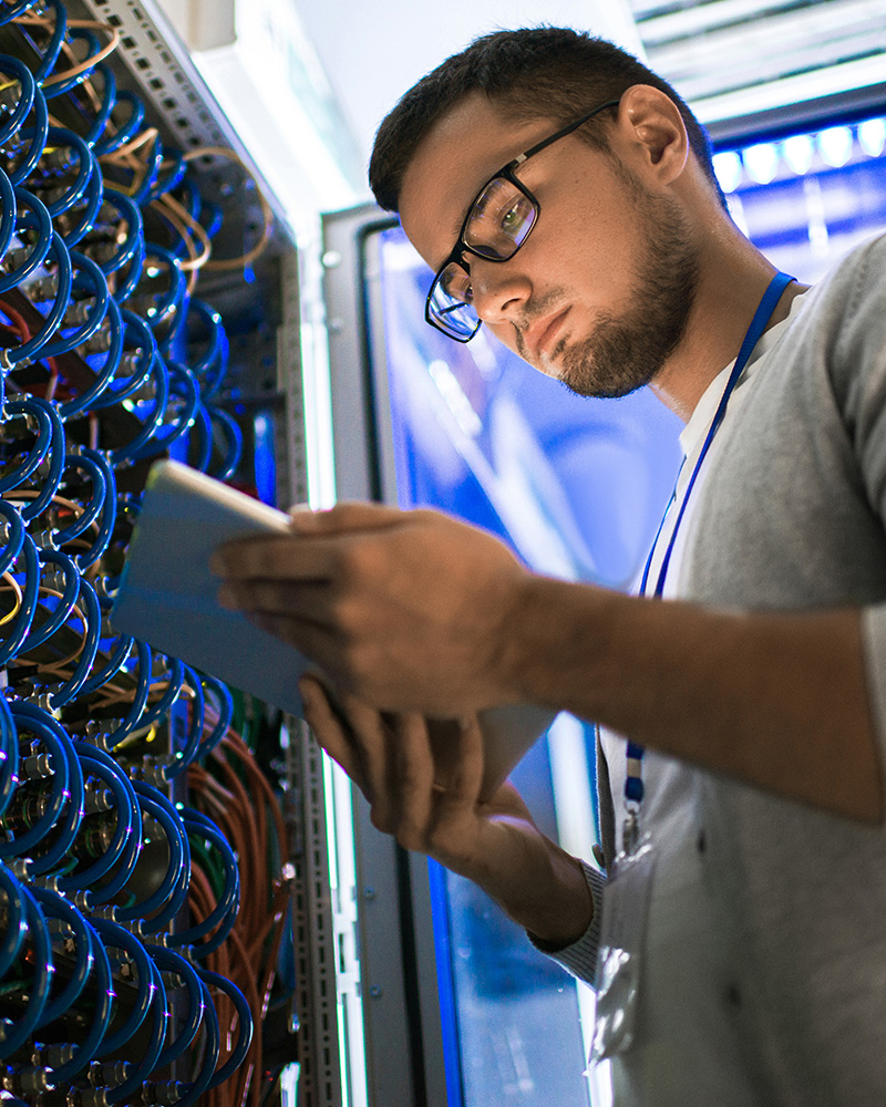 A close-up of a technician installing network cables, connecting wires to a network switch or patch panel.